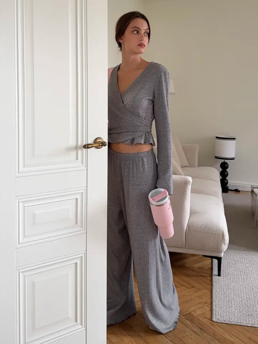 woman posing indoors wearing gray ribbed wrap top and holding pink tumbler