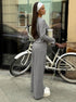side view of woman wearing gray ribbed lounge set standing beside a bicycle