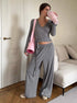 woman posing indoors wearing gray ribbed wrap crop top and wide leg pants with pink bag