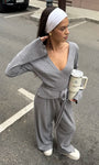 woman wearing gray ribbed wrap crop top and wide leg pants standing on street holding a tumbler