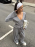 woman wearing gray ribbed wrap crop top and wide leg pants standing on street holding a tumbler