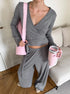 close-up of gray ribbed wrap crop top and pants with woman holding tpink umbler
