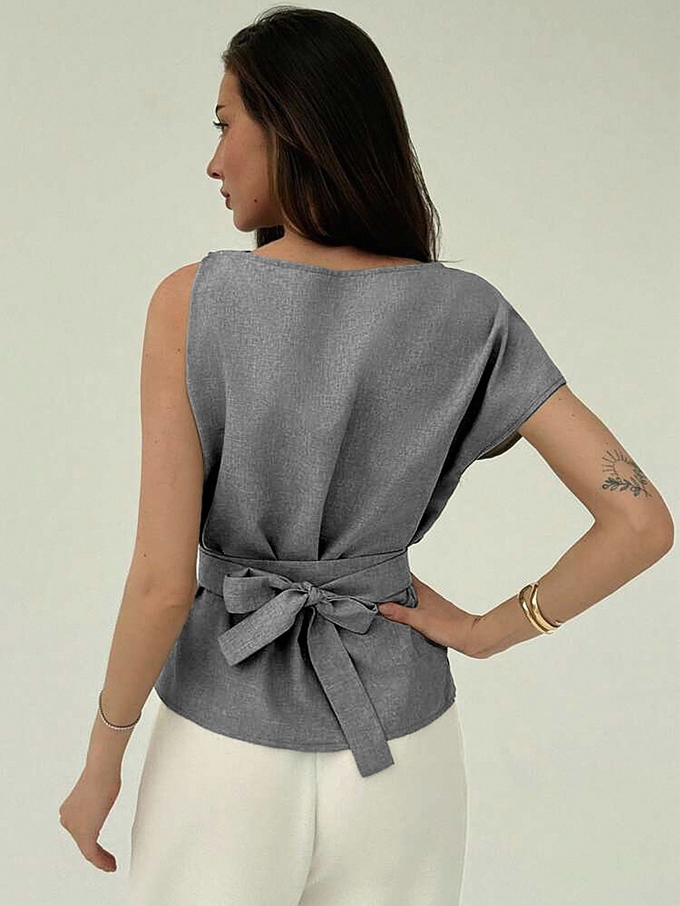 Back view of gray sleeveless top with waist tie and wide shoulders

