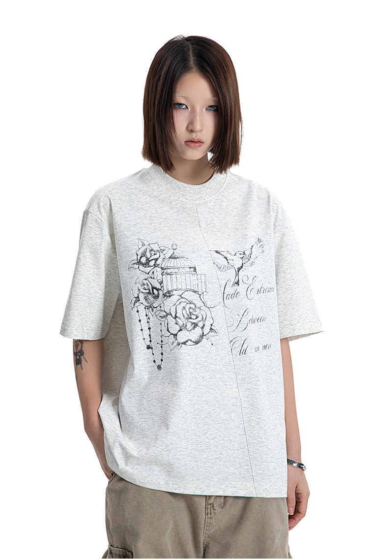 Front view of a model in a heather light grey t-shirt featuring hand-drawn rose and bird graphics.
