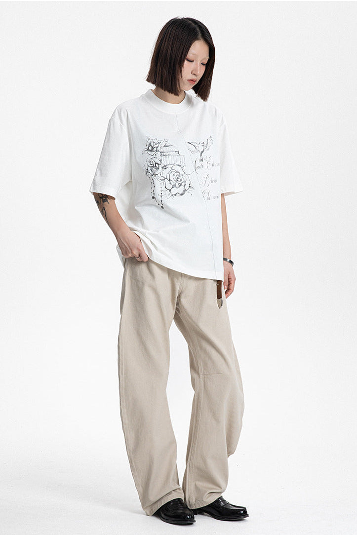 Model posed in a white short sleeve graphic crewneck t-shirt and wide-leg casual pants.