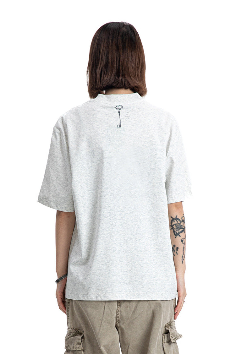 Rear view of a model in a heather light grey crewneck t-shirt showing a small back key print.