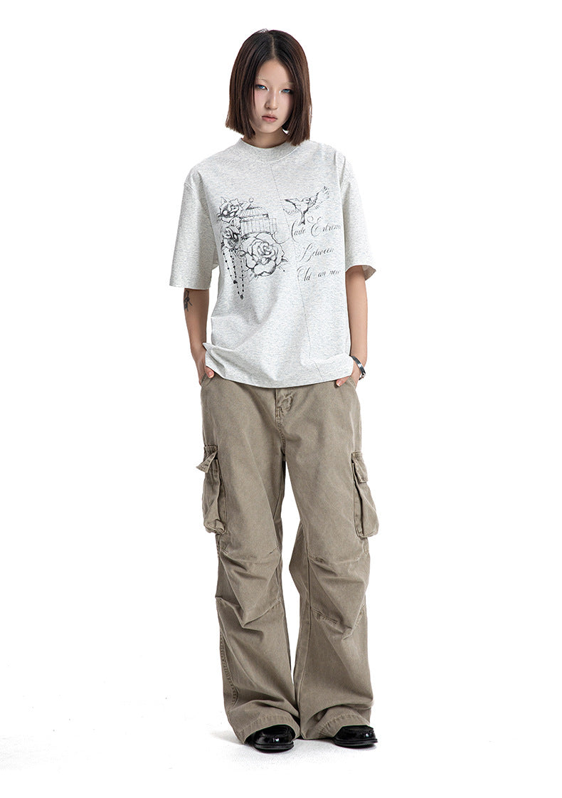 Full body shot of a model wearing a heather grey graphic tee with tan cargo pants and black shoes.