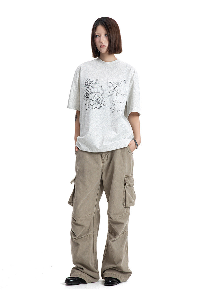 Full body view of a model standing in a loose fit heather grey short sleeve graphic t-shirt.
