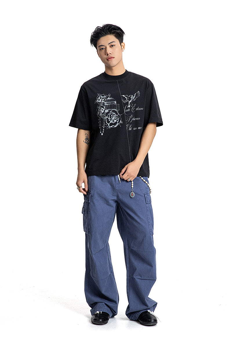 Full body view of a male model in a black relaxed graphic t-shirt paired with blue cargo trousers.