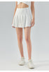 Front view of white tennis skirt with high waist and flared silhouette, styled with sneakers.