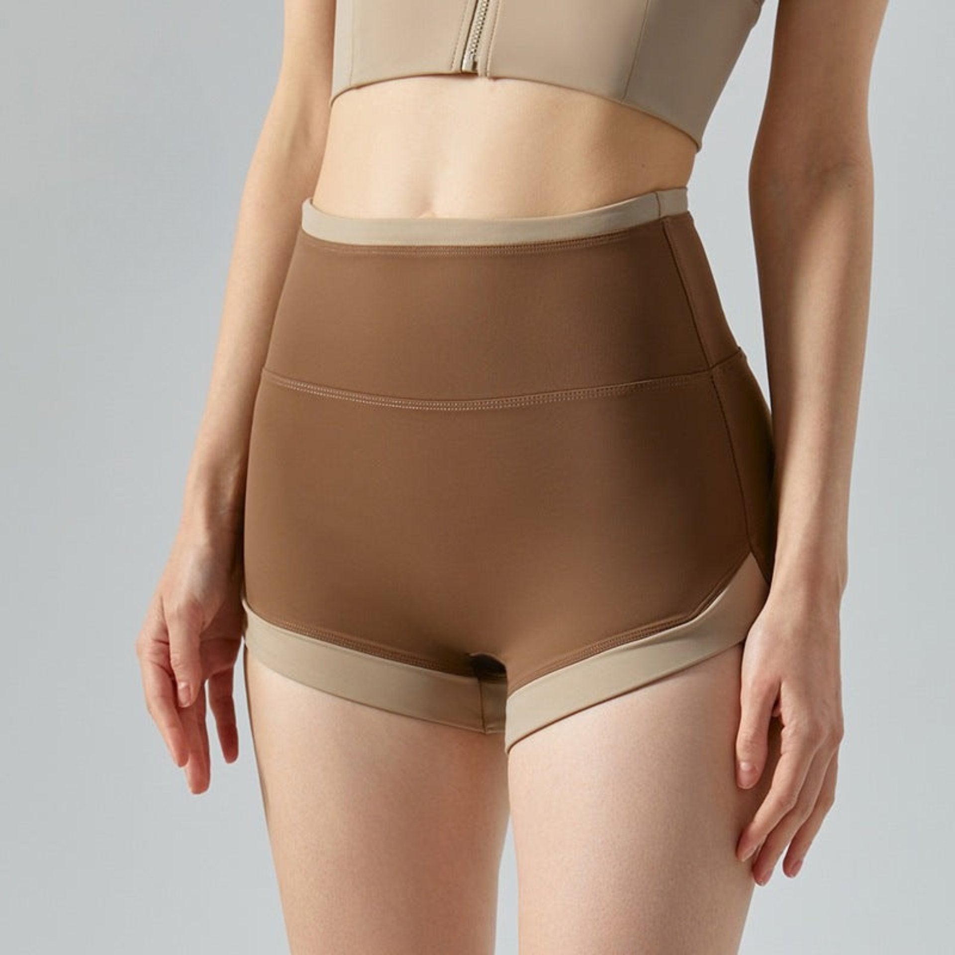 Model showcases chocolate brown fitness shorts with beige accents.