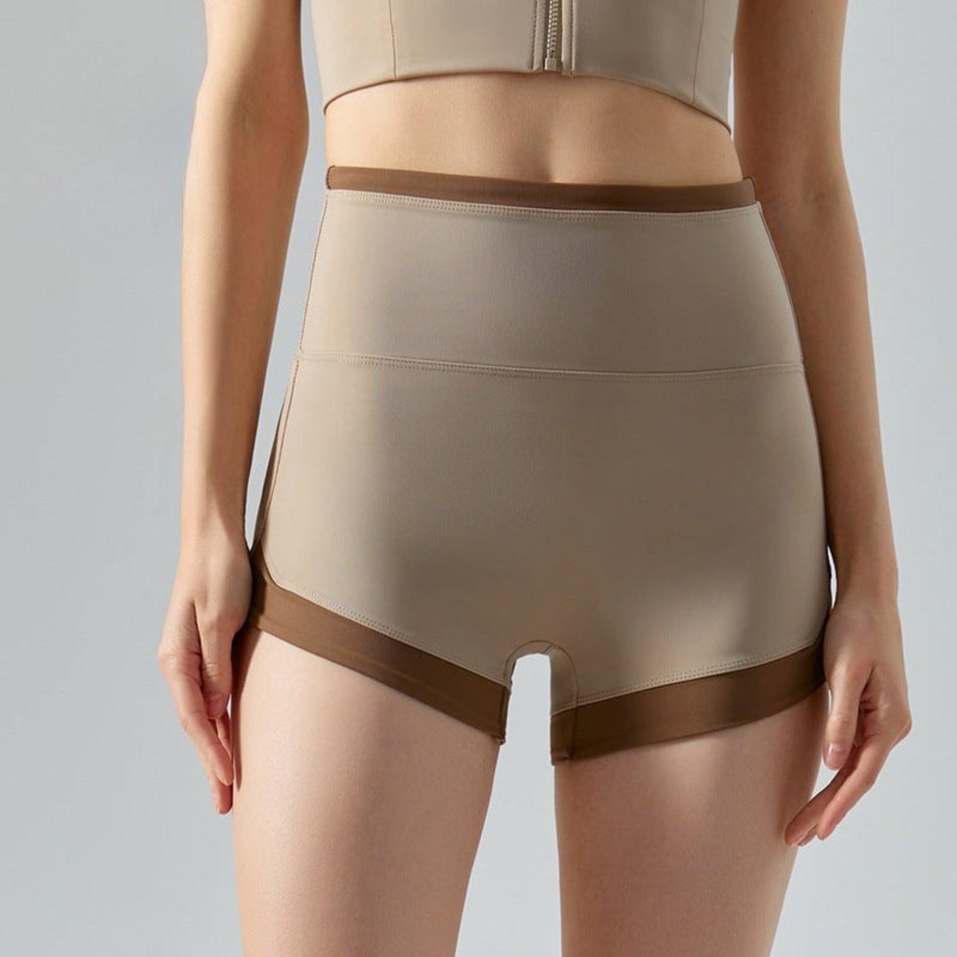 High-waisted khaki shorts with dark brown trim styled on model.