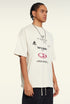 Man models cream oversized graphic tee with layered futuristic text designs.