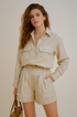 Woman wearing a khaki set with a shirt and shorts on a beige background