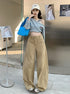 Front view of khaki curved hem wide-leg jeans paired with studded denim top.