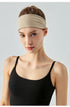 Woman wearing a wide khaki headband and black sports top, front view.