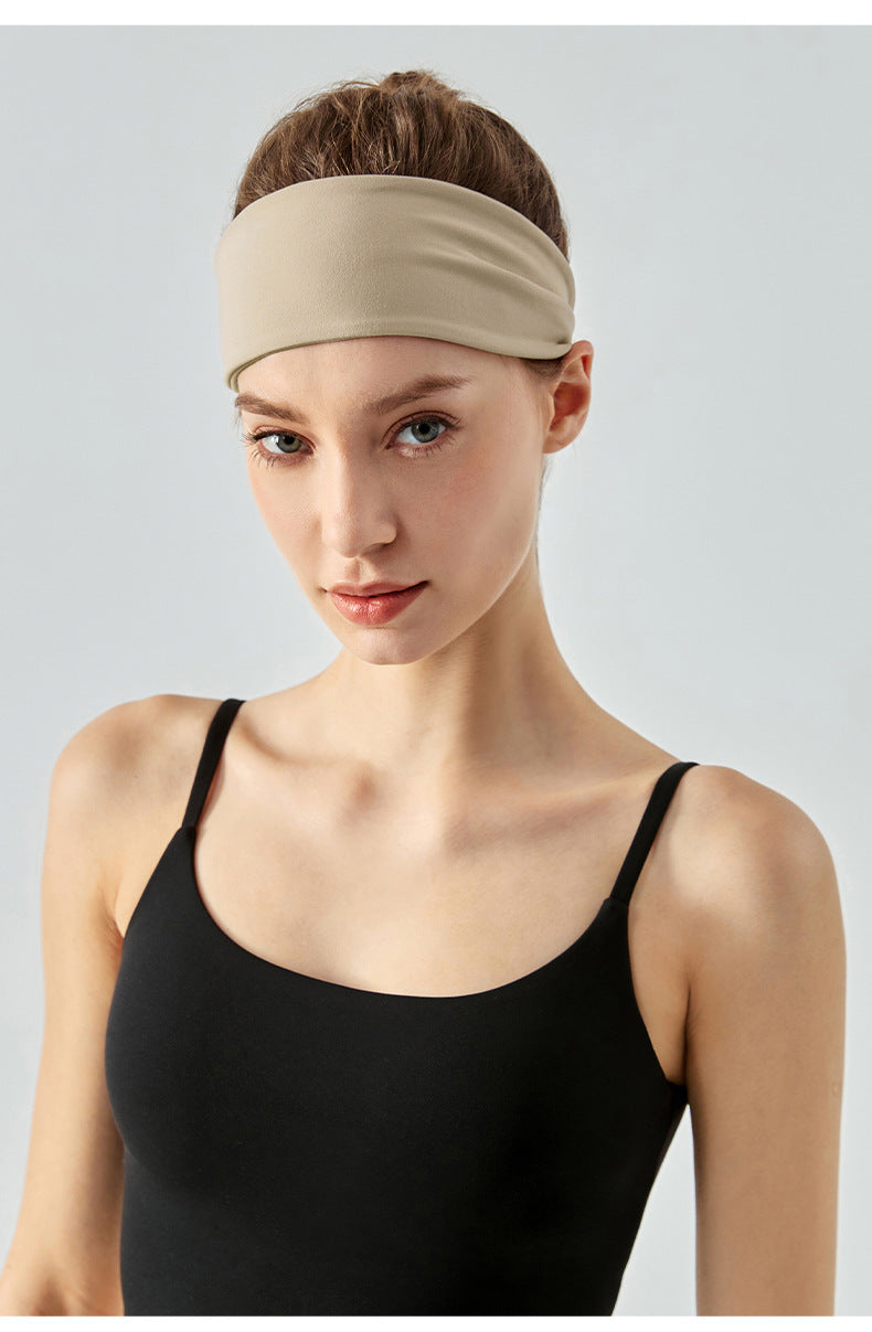 Woman wearing a wide khaki headband and black sports top, front view.