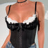 Close-up of a black lace corset top with white ruffle trim and jeweled bow detail.