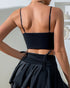 Back view of a woman wearing a simple black bandeau-style back corset and a ruched black mini skirt.