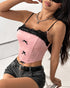 Woman sitting on a clear chair wearing a pink lace-trimmed corset and dark denim shorts with a black belt.
