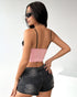Back view of a woman wearing a simple pink bandeau-style back corset and a ruched black mini skirt.