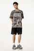 Model in grey Liberalism tee and black shorts, facing forward with hands behind back.