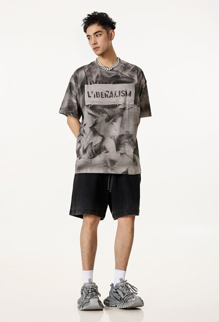 Model in grey Liberalism tee and black shorts, facing forward with hands behind back.