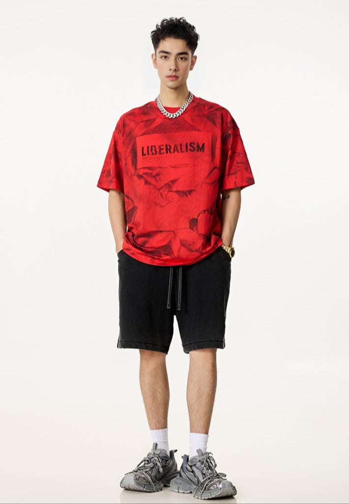 Model in red Liberalism tee and black shorts, standing front-facing with hands in pockets.
