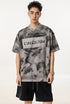 Man wears oversized gray graphic tee with “Liberalism” text and black shorts.