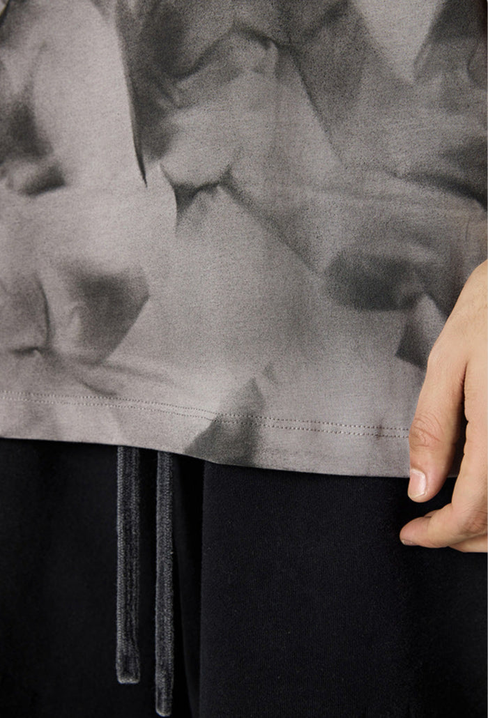 Close-up of tee hem and drawstrings over black shorts.