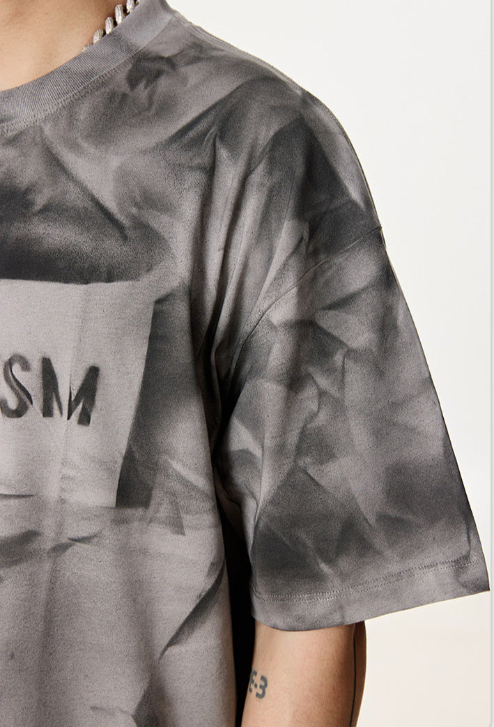 Close-up of gray graphic tee sleeve and upper chest showing “Liberalism” print.