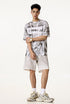Man models white oversized graphic tee with “Liberalism” text and light shorts.