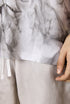Close-up of tee hem and hand resting on beige shorts.