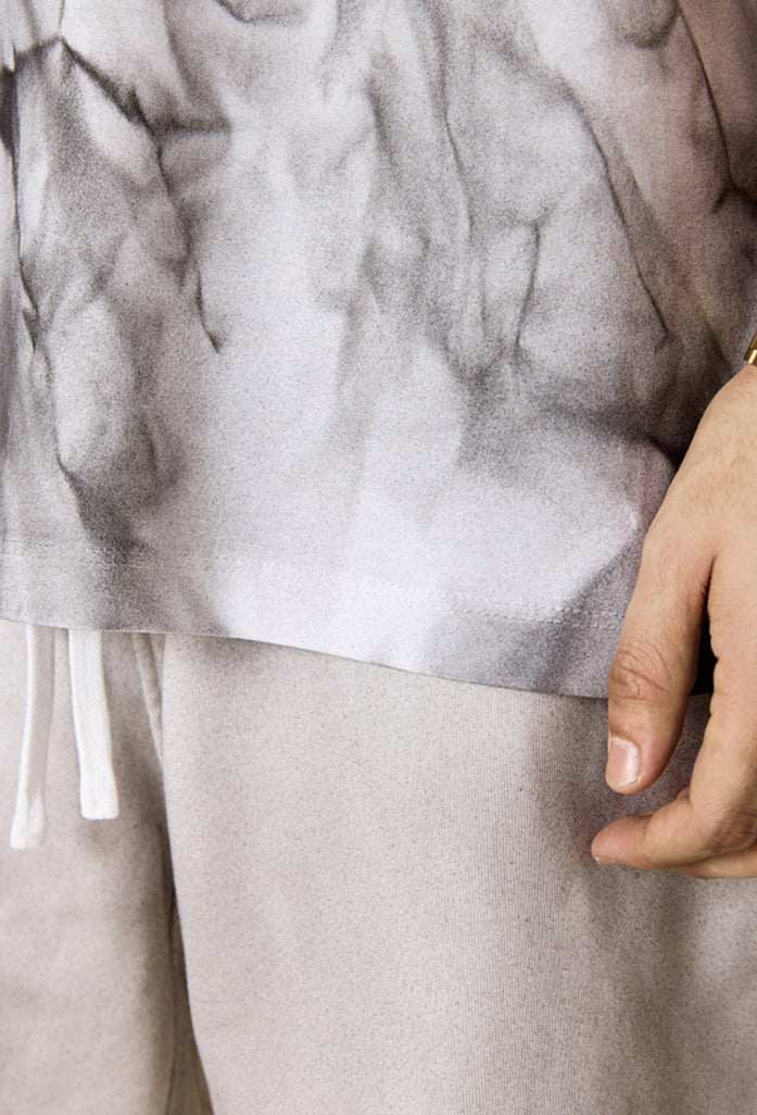 Close-up of tee hem and hand resting on beige shorts.