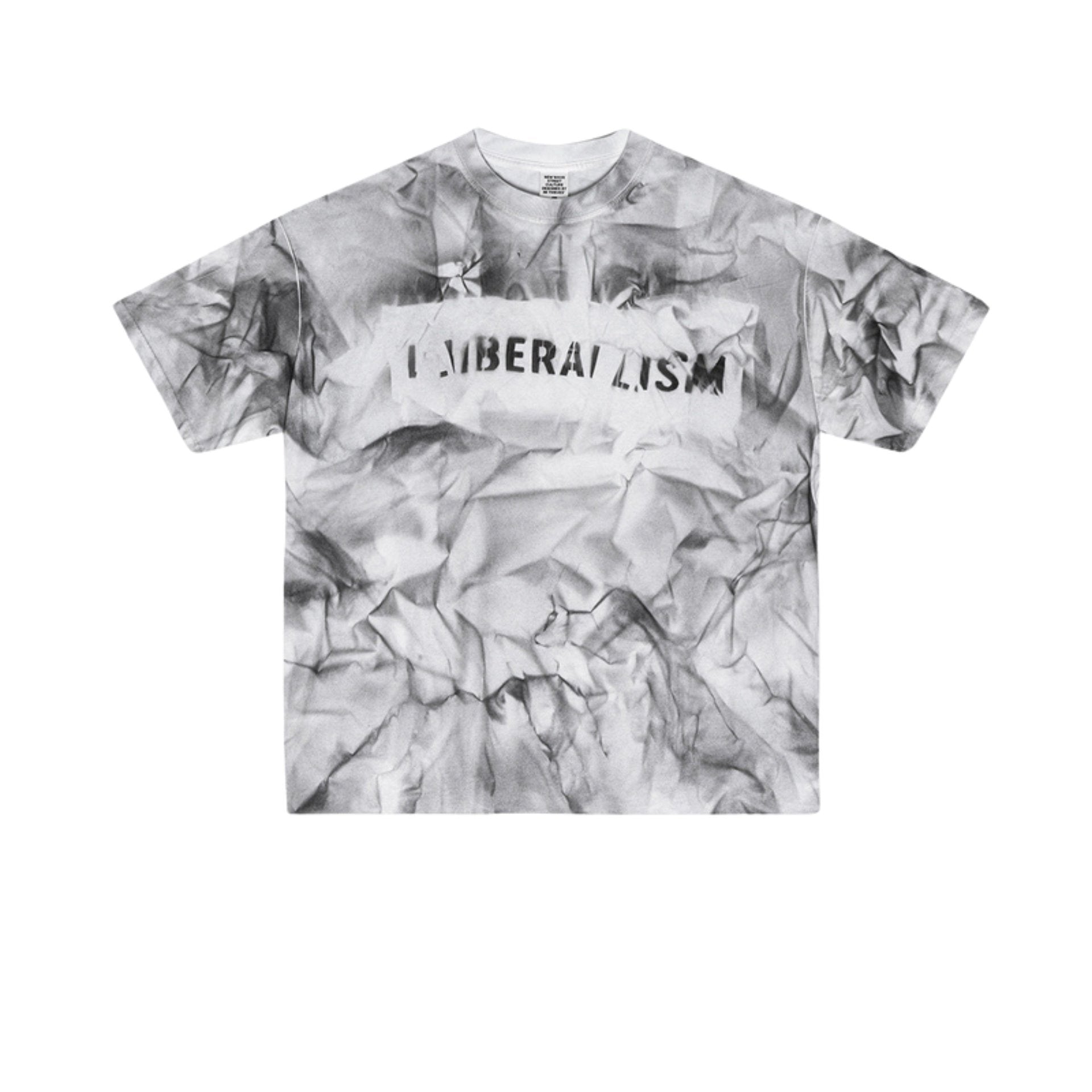 Flat lay of white graphic tee with black “LIBERALISM” stencil text and smoky crumple print.
