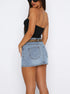 Back view of model in a black strapless top and light blue denim mini skirt with back pockets.