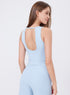 Angled back view of woman in light blue workout tank with scoop back and matching leggings.