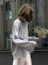Side view of woman in light gray backless knit sweater outdoors