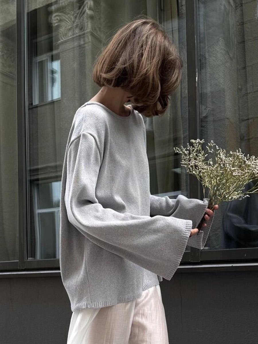 Side view of woman in light gray backless knit sweater outdoors