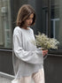 Woman wearing light gray knit sweater front view outdoors