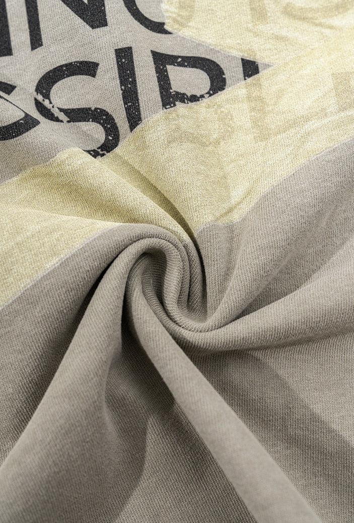 Twisted fabric close-up of light grey tee showing print texture.
