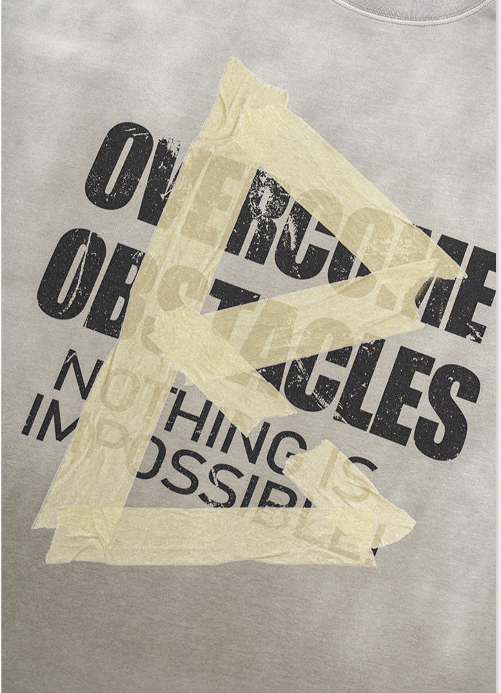Front graphic detail of light grey tee with motivational text and taped design.