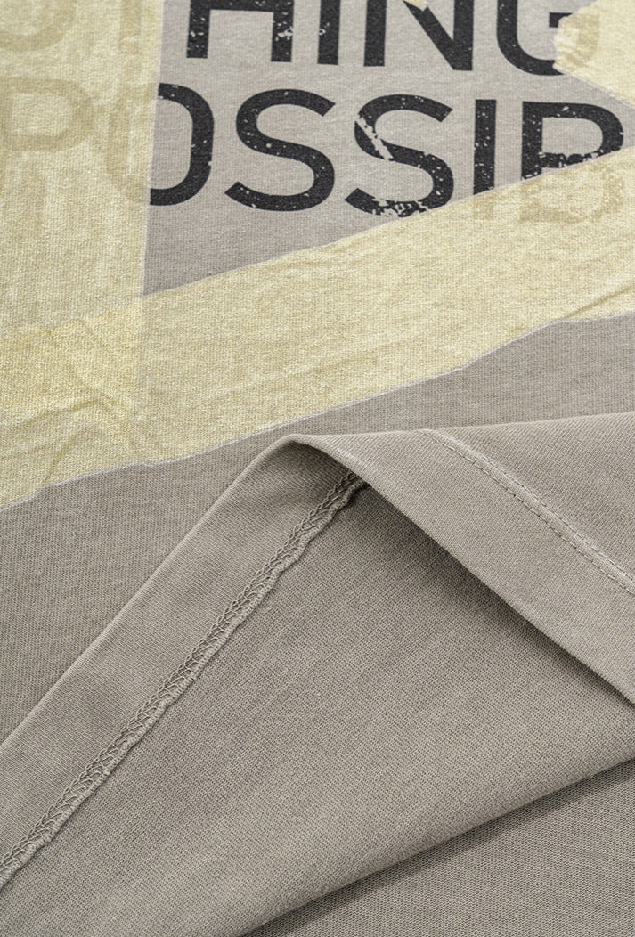 Inside-out view of hem stitching on light grey graphic tee.