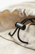 Close-up of beige linen trousers with adjustable black drawstring closure