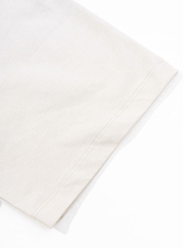Hem detail on short sleeve of apricot t-shirt.