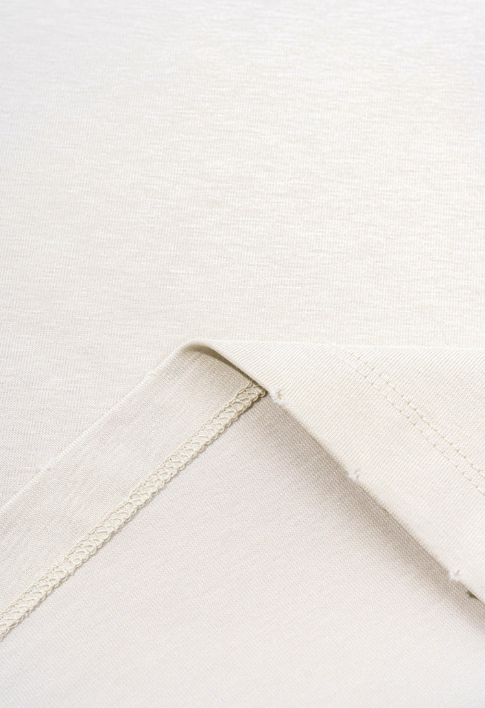 Inside-out stitching and fabric texture of cream t-shirt.