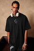 Man modeling black loading tee, standing with relaxed pose.