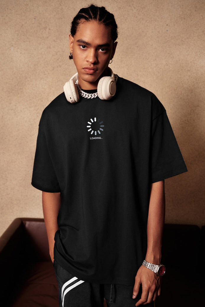 Man modeling black loading tee, standing with relaxed pose.
