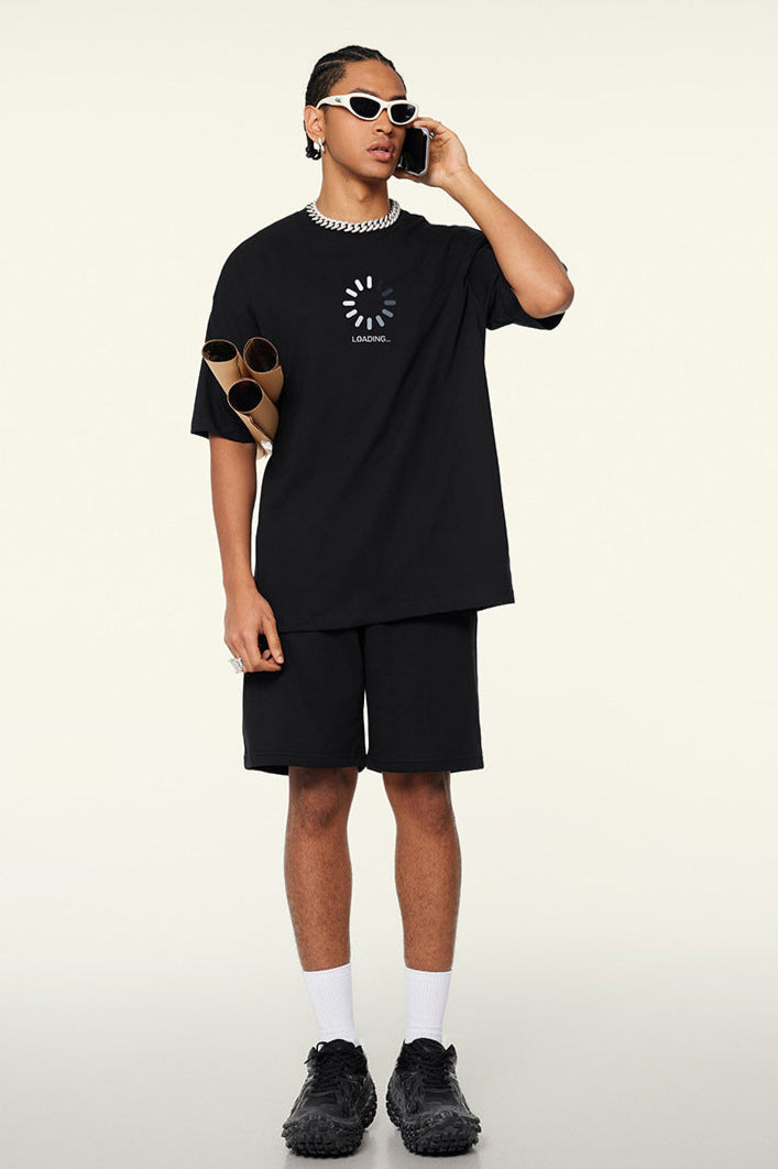 Man on phone wearing black loading tee and sunglasses.