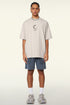 Man wearing cream loading tee with blue shorts and sneakers.